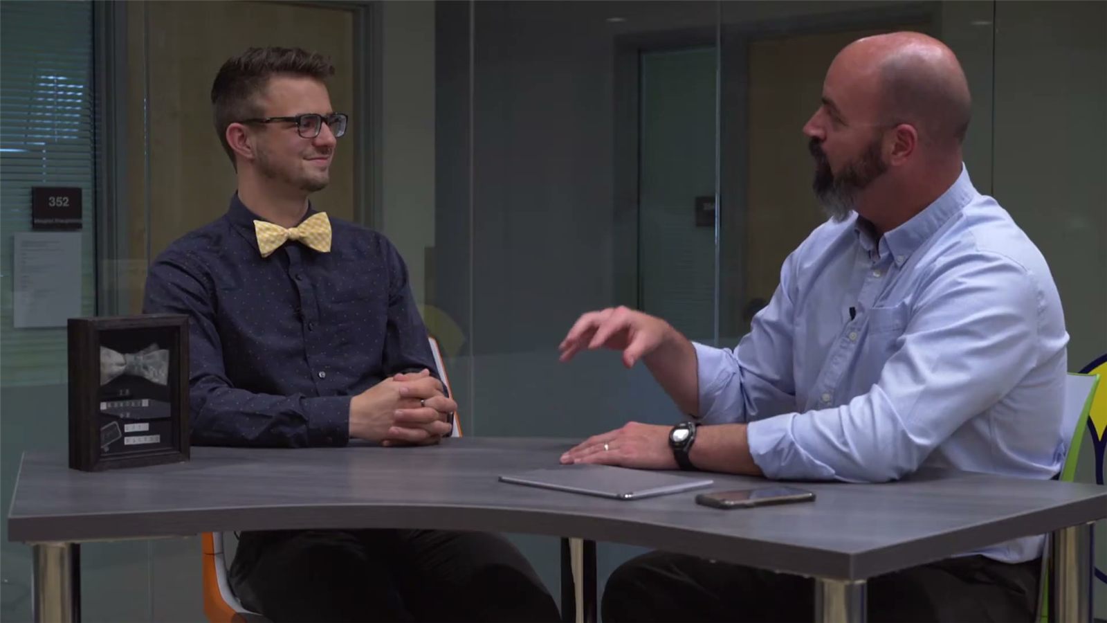 Paul Hunter, in a gold bowtie, and Ken Sagendorf talk across a table.