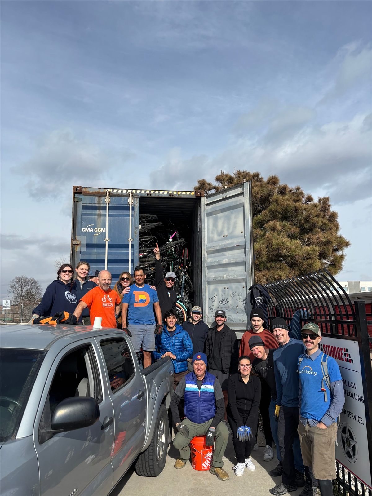 Volunteers stand in front of an open shipping container loaded with bikes for Bicycles 4 Humanity.