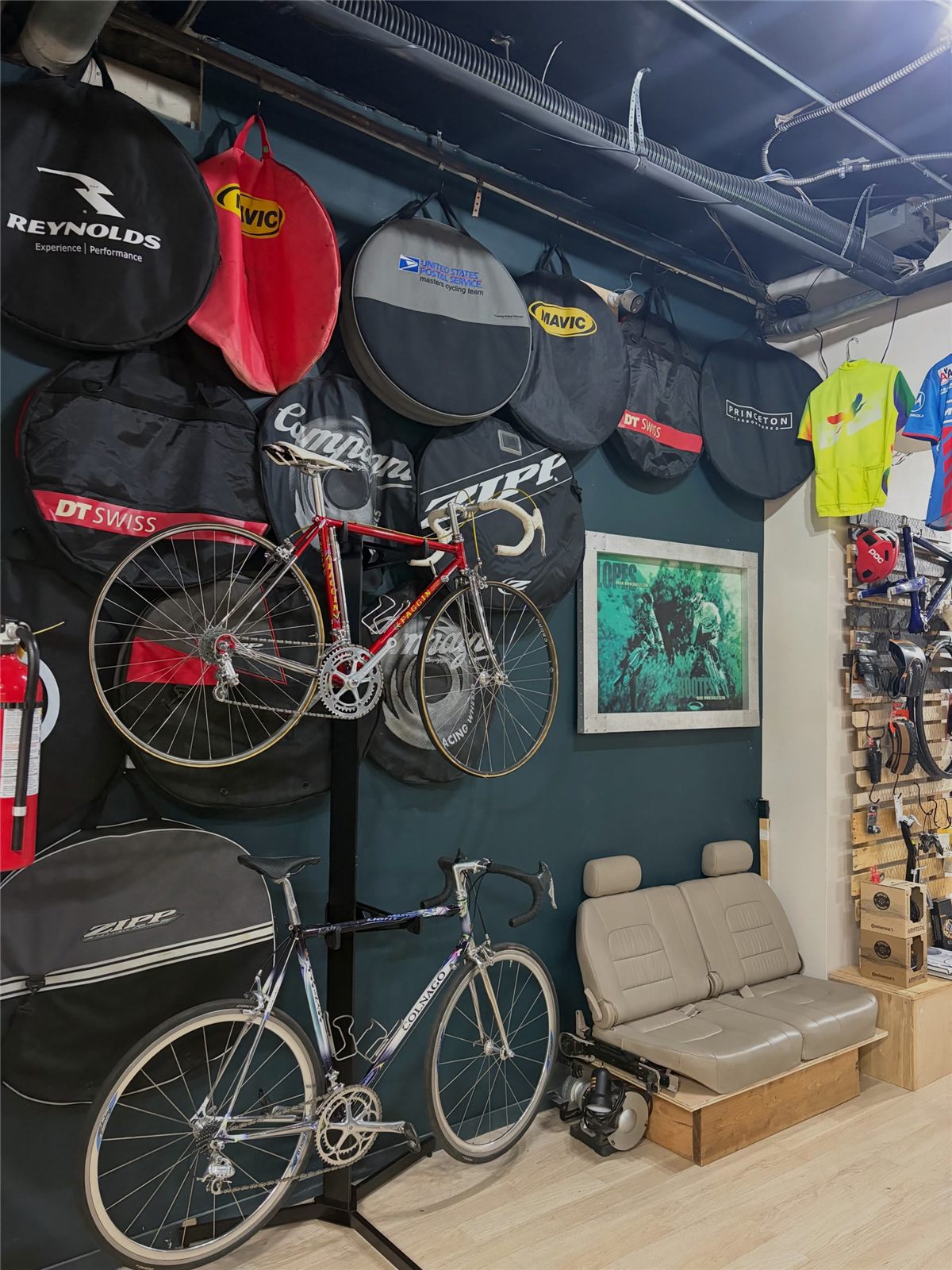 Inside the Traveling Ground shop: wheel bags and road bikes hang on a dark wall above a small lounge.