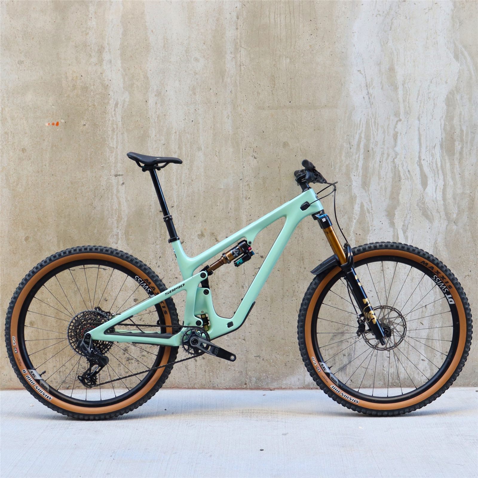 A mint-green Yeti mountain bike with tan-wall tires stands against a concrete wall.
